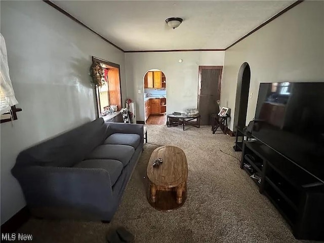 carpeted living room with arched walkways and ornamental molding