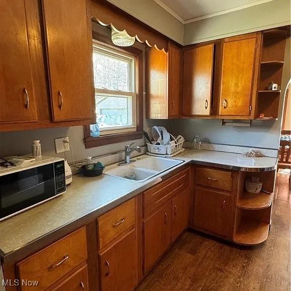 kitchen with brown cabinetry, black microwave, open shelves, and a sink