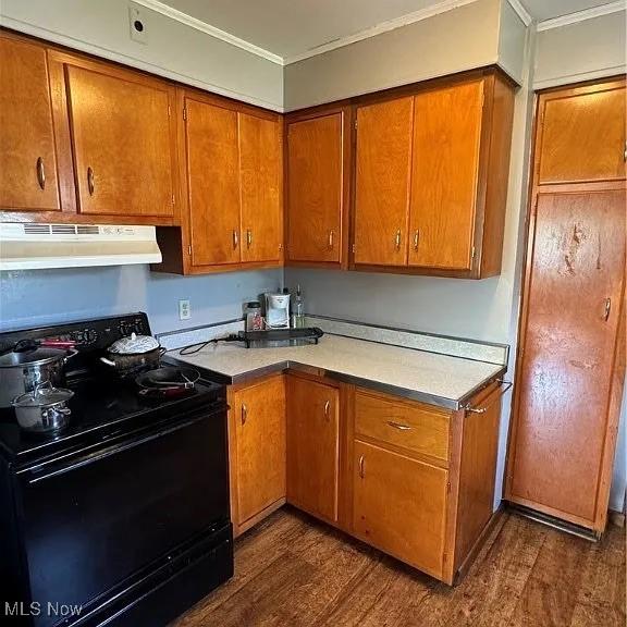 kitchen with brown cabinets, light countertops, black range with electric stovetop, and under cabinet range hood