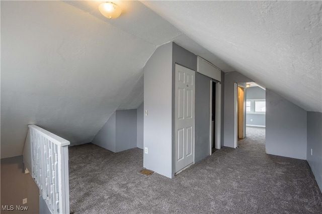 additional living space featuring carpet, vaulted ceiling, and a textured ceiling