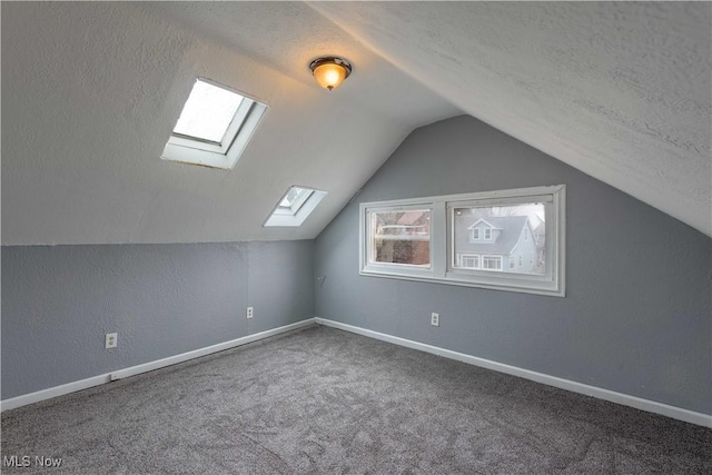 additional living space featuring carpet, lofted ceiling, a textured wall, a textured ceiling, and baseboards