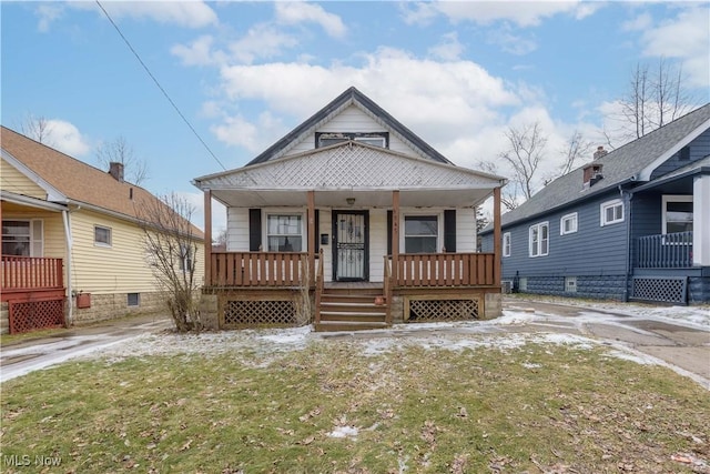 bungalow-style house featuring covered porch and a front lawn