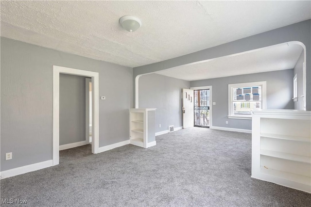 unfurnished living room featuring a textured ceiling, carpet, and baseboards