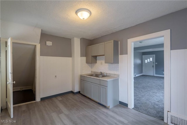 kitchen with visible vents, gray cabinets, a textured ceiling, light countertops, and a sink