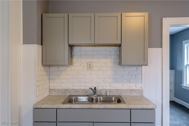 kitchen featuring gray cabinets, light countertops, a sink, and decorative backsplash