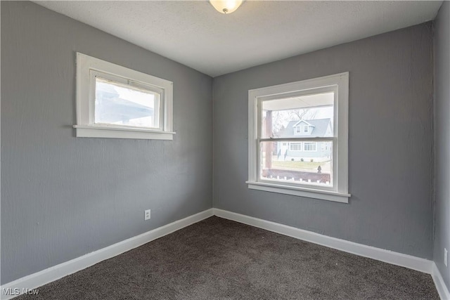 empty room with dark colored carpet and baseboards