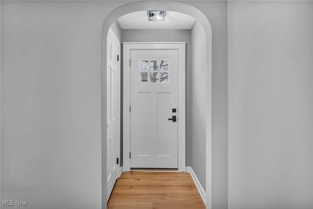 entryway featuring arched walkways and light wood finished floors