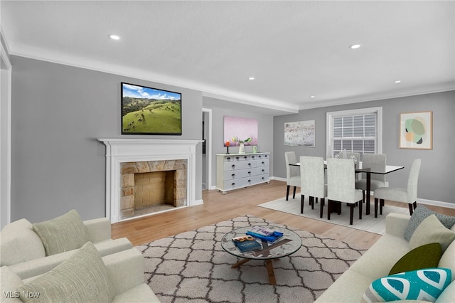 living room with light wood-style floors, recessed lighting, crown molding, and a fireplace