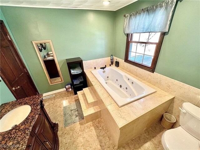 bathroom with a jetted tub, toilet, and vanity