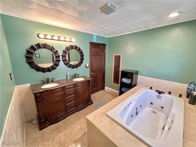 bathroom with double vanity, a tub with jets, a sink, and visible vents