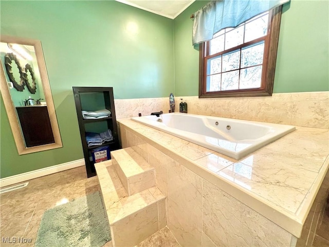 bathroom featuring baseboards, visible vents, and a tub with jets