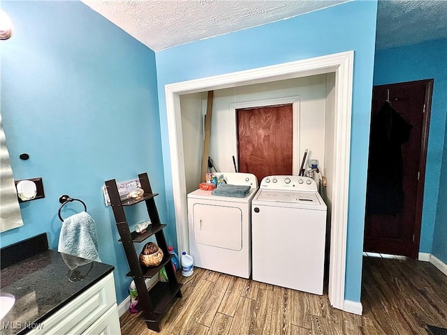 laundry area featuring dark wood-style flooring, a textured ceiling, separate washer and dryer, laundry area, and baseboards