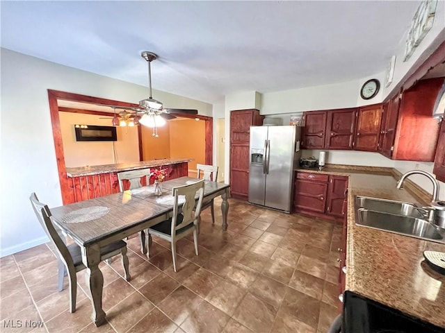 kitchen with black microwave, a sink, reddish brown cabinets, dishwasher, and stainless steel fridge