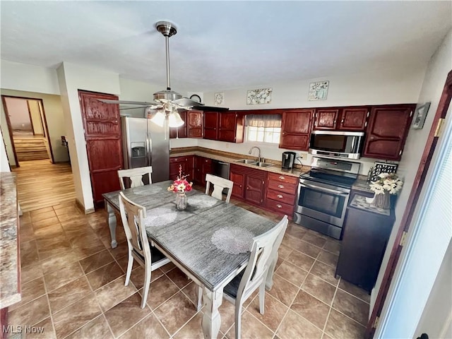 kitchen with appliances with stainless steel finishes, a sink, ceiling fan, dark brown cabinets, and dark tile patterned floors