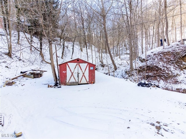 snowy yard featuring a storage shed and an outdoor structure