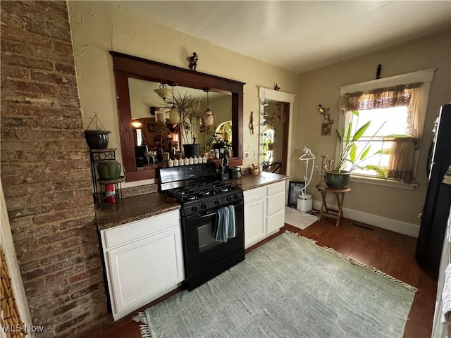 kitchen with dark wood-style floors, dark countertops, visible vents, black gas range, and white cabinetry