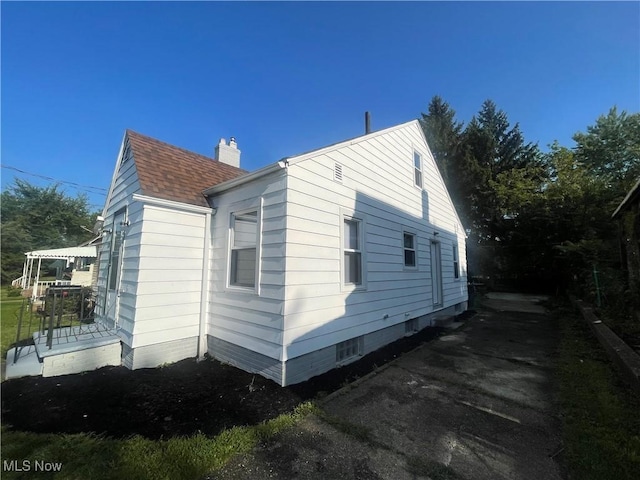 view of property exterior with a chimney and roof with shingles