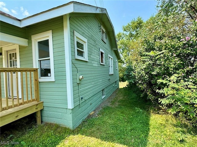 view of side of home with a lawn and a wooden deck