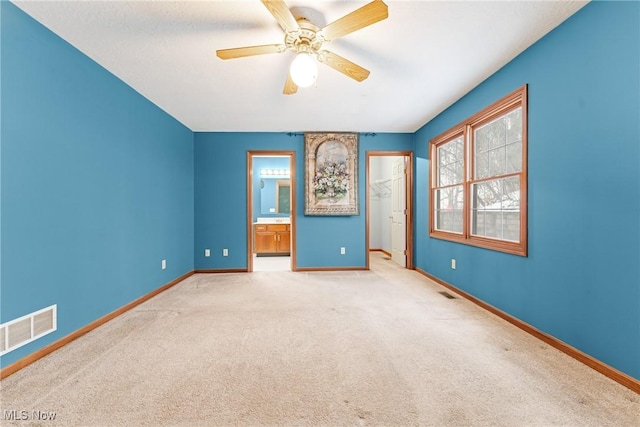 unfurnished bedroom featuring carpet, visible vents, baseboards, and ensuite bathroom