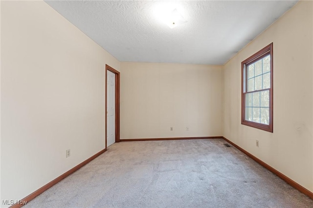 empty room with visible vents, baseboards, a textured ceiling, and light colored carpet