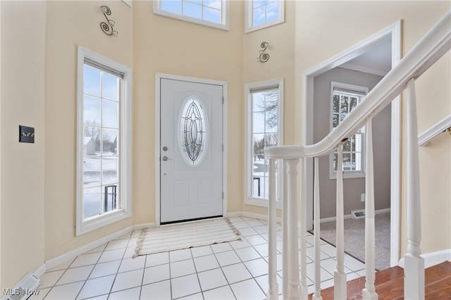 foyer with baseboards, a high ceiling, stairway, and light tile patterned flooring