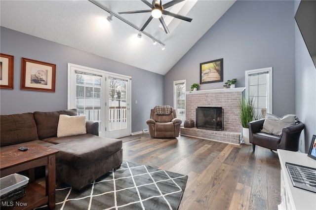 living area with ceiling fan, high vaulted ceiling, a fireplace, wood finished floors, and baseboards