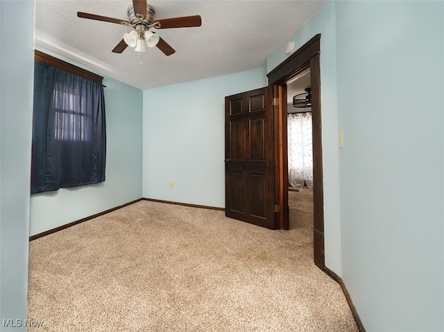 unfurnished bedroom featuring light colored carpet, a textured ceiling, and baseboards