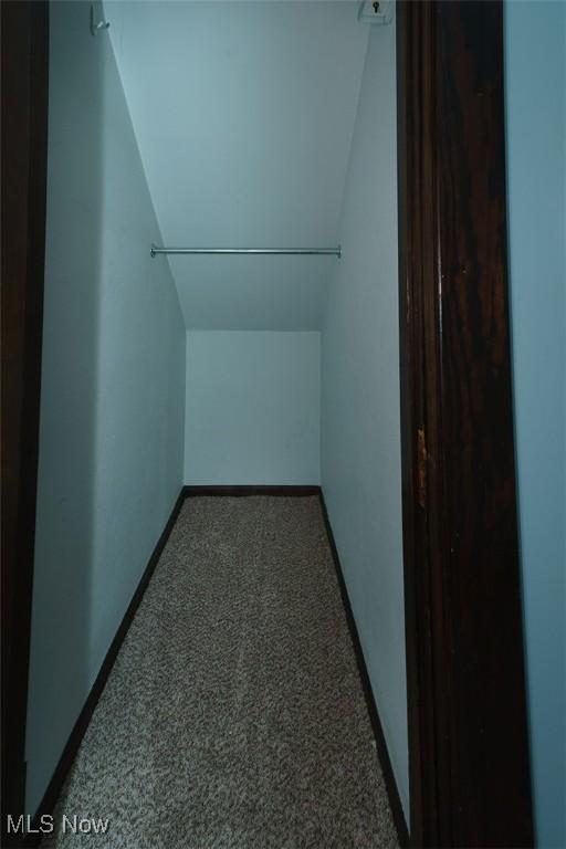 additional living space with lofted ceiling, dark colored carpet, and baseboards