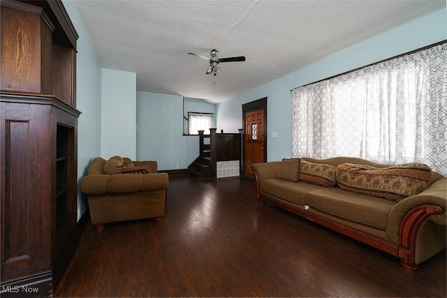 living area with dark wood-style floors, stairway, a textured ceiling, and a ceiling fan