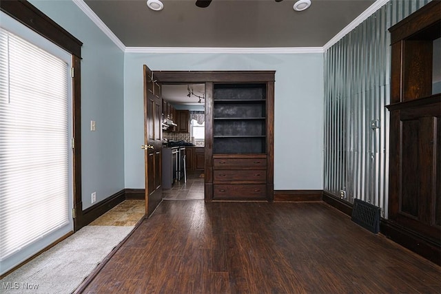 interior space featuring baseboards, dark wood-style flooring, visible vents, and crown molding