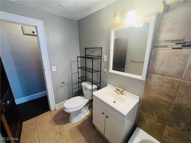 full bathroom with tile patterned flooring, toilet, vanity, baseboards, and a bathtub