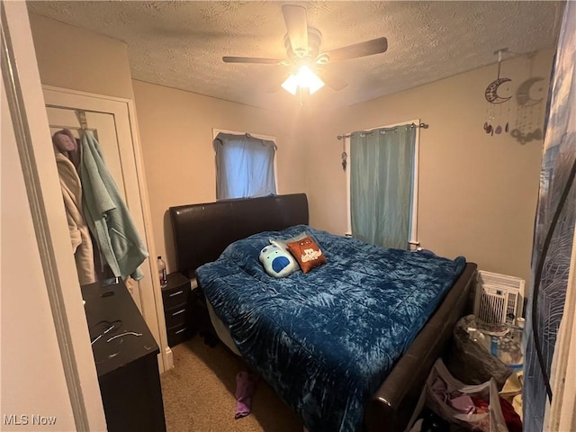 carpeted bedroom featuring a ceiling fan and a textured ceiling