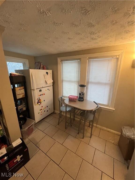 dining area with light tile patterned floors, baseboards, and a textured ceiling