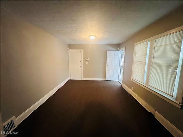 unfurnished room with a textured ceiling and baseboards