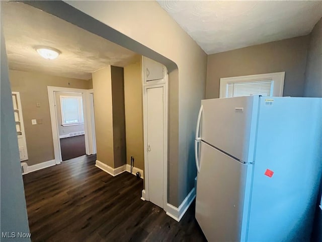 kitchen featuring baseboards, dark wood finished floors, and freestanding refrigerator