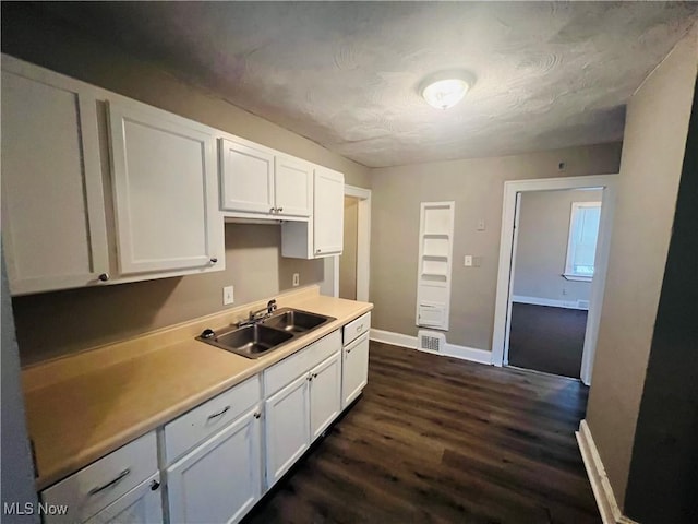 kitchen with visible vents, dark wood-type flooring, light countertops, white cabinetry, and a sink