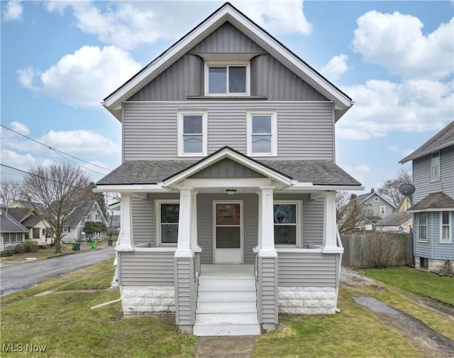 view of front of property with a front yard, a porch, and roof with shingles