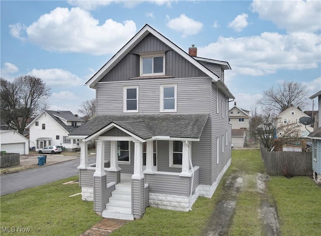 view of front of property with covered porch, a shingled roof, a chimney, and a front lawn