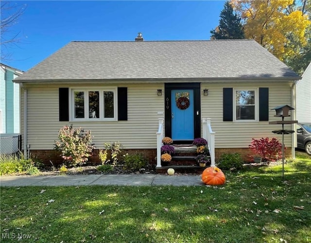 view of front facade with entry steps, a shingled roof, and a front yard