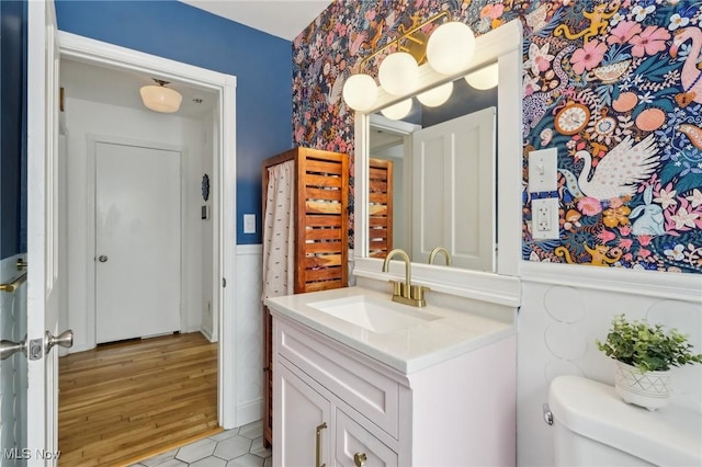 bathroom featuring toilet, wainscoting, and vanity