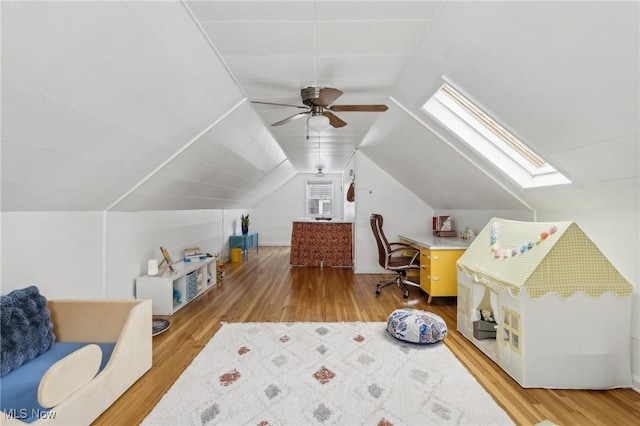 interior space featuring vaulted ceiling with skylight, ceiling fan, and wood finished floors