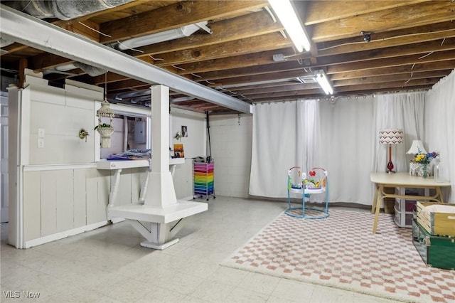 unfinished basement with electric panel and tile patterned floors