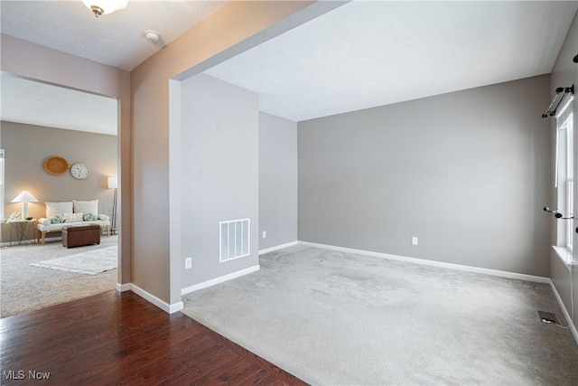 empty room featuring dark carpet, visible vents, and baseboards