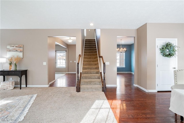 entrance foyer with dark wood-style floors, baseboards, stairway, and an inviting chandelier