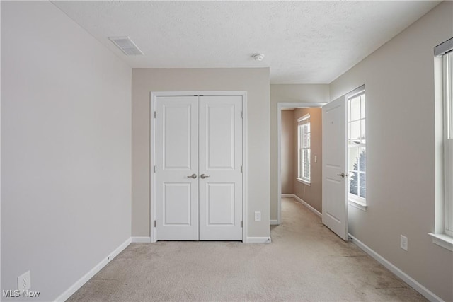 unfurnished bedroom featuring a closet, light colored carpet, visible vents, and baseboards