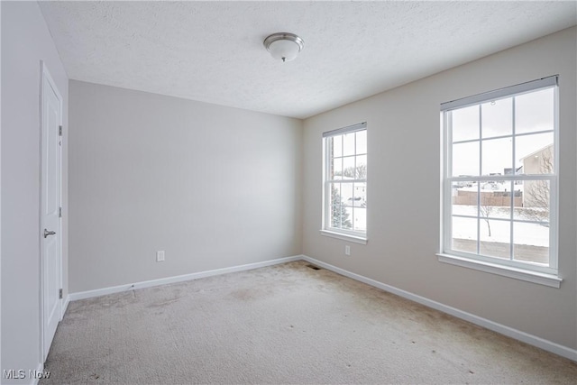 unfurnished room featuring a textured ceiling, light carpet, and baseboards