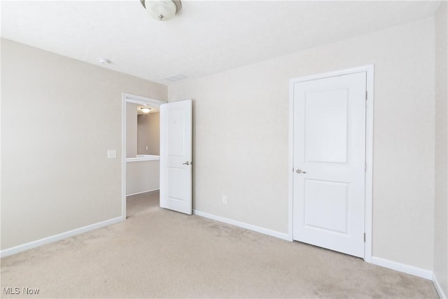 empty room featuring light carpet and baseboards