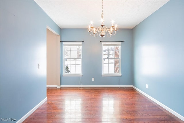 spare room featuring a textured ceiling, baseboards, and wood finished floors