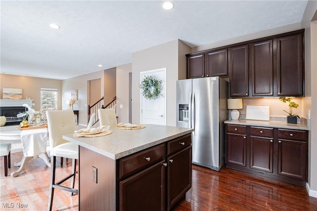 kitchen with a center island, dark brown cabinetry, and stainless steel fridge with ice dispenser