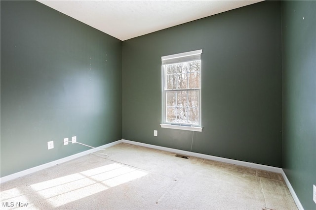 spare room featuring light carpet, visible vents, and baseboards